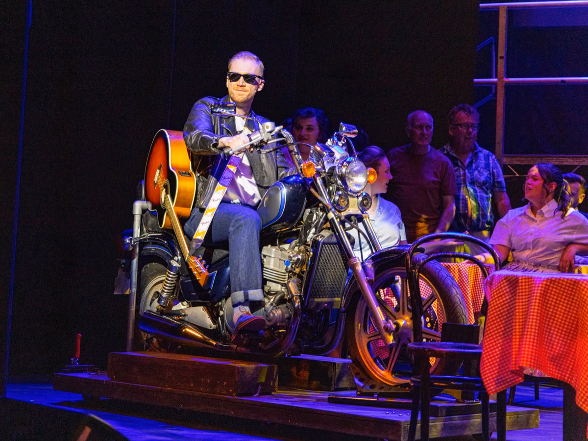 Jamie Edwardson on stage on a motorcycle prop
