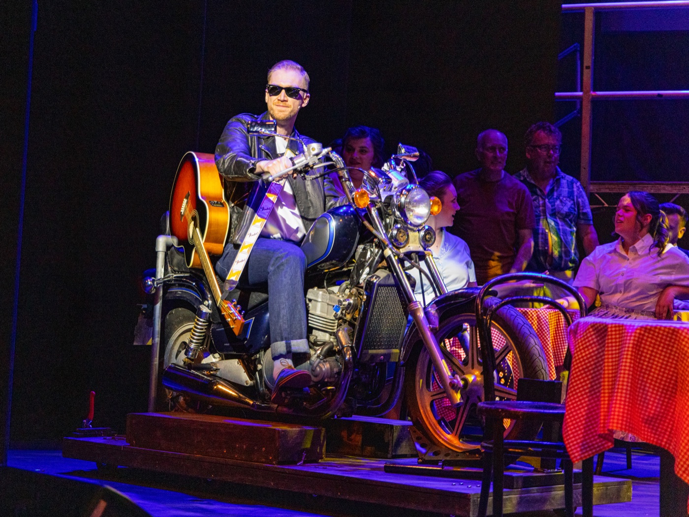 Jamie Edwardson on stage on a motorcycle prop